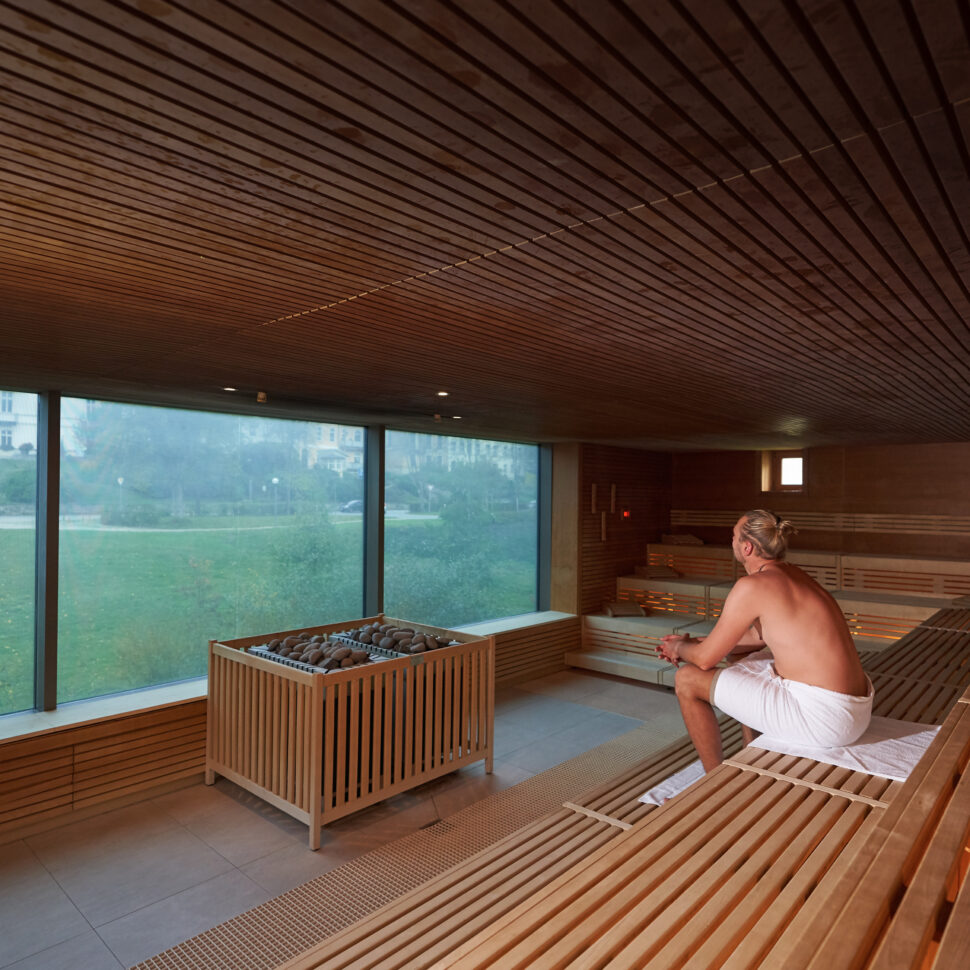 Eine Frau sitzt in der Panorama-Sauna mit geschlossenen Augen und den Kopf im Nacken