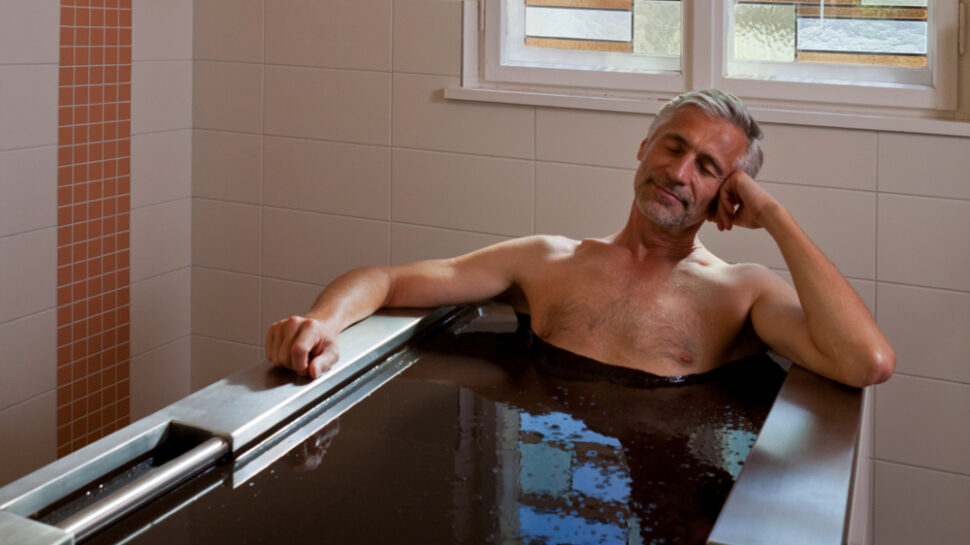 Ein Mann liegt mit geschlossenen Augen in einer Naturmoorbadewanne