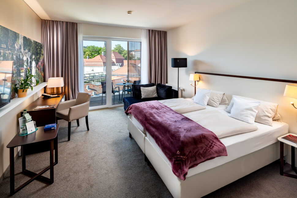 Doppelbettzimmer mit kleinem Schreibtisch und kleinem Balkon