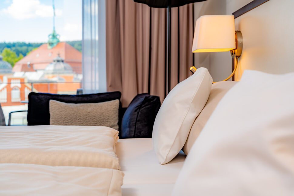 Detailansicht vom Bett-Kopfteil mit Kissen, Decke und einer Nacht-Lampe