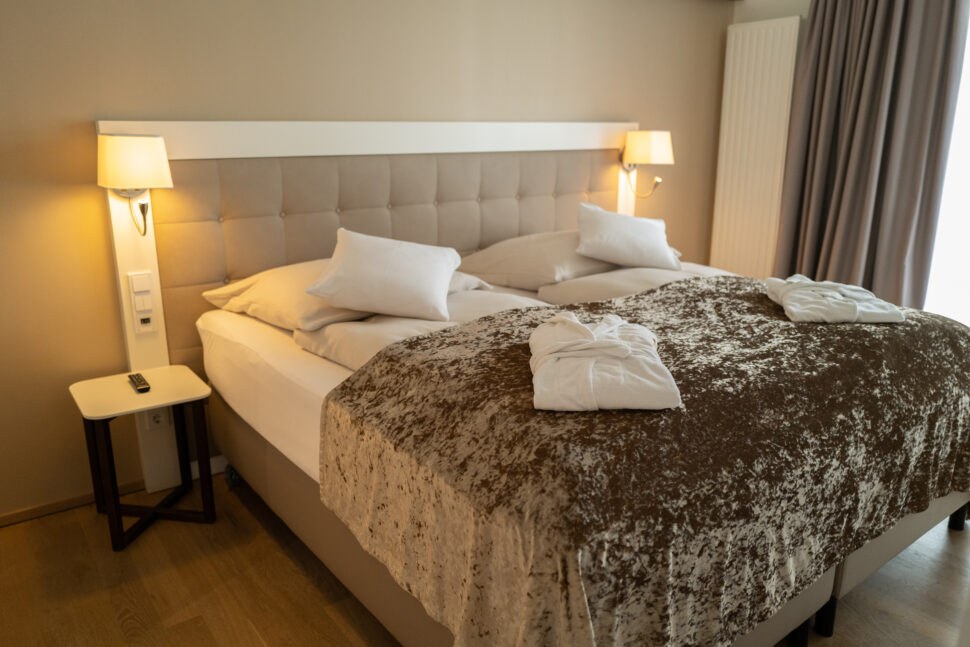 Detailansicht eines Doppelbettes, mit Tagesdecke und zwei Bademänteln