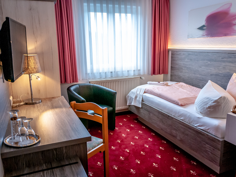 Goldener Anker Einzel-Zimmer Ansicht mit Bett, kleinem Schreibtisch und Fernseher