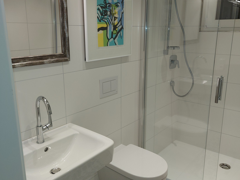 Blick ins Badezimmer auf Waschbecken, Toilette und Dusche